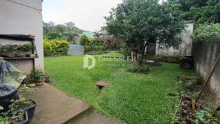 Vista externa de um quintal gramado com árvores e muro em Lajeado.