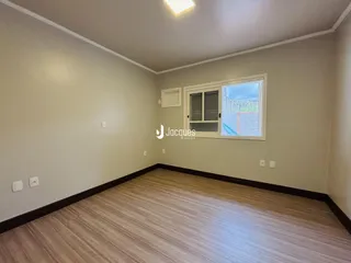 Foto de uma sala com piso de madeira clara e janela.