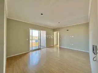 Sala ampla com piso de madeira clara e porta de vidro que dá para o exterior.
