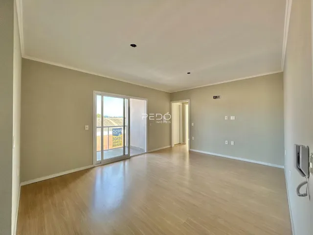Sala ampla com piso de madeira clara e porta de vidro que dá para o exterior.
