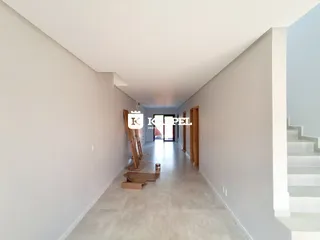 Hall de entrada longo com paredes brancas e portas de madeira.