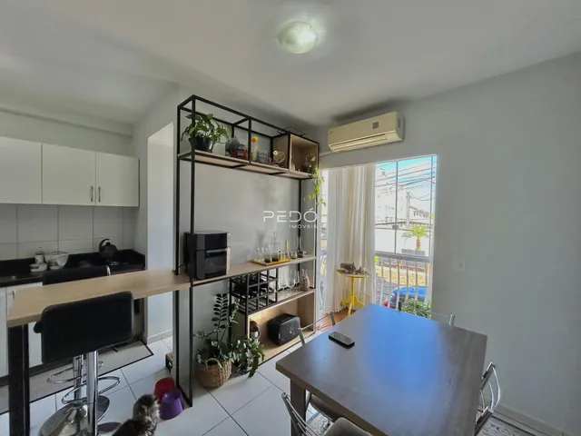 Interior de uma sala de estar com cozinha e área de jantar em um imóvel no Brasil.