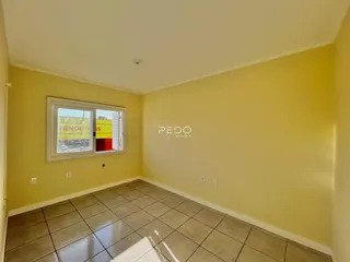 Interior de uma sala com piso de cerâmica e parede amarela.