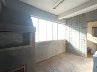 Interior de uma sala com janela grande e piso de cerâmica.