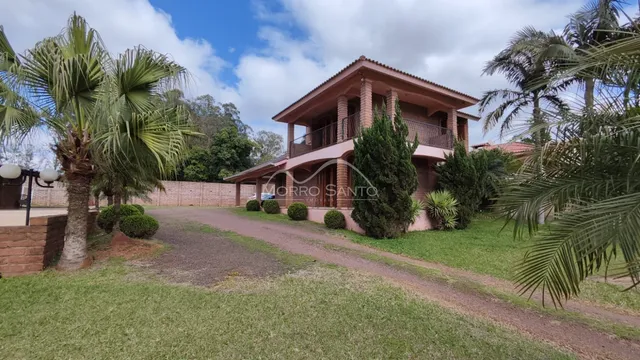 Fachada de uma casa de dois andares em Lajeado, Brasil, com jardim e palmeiras.