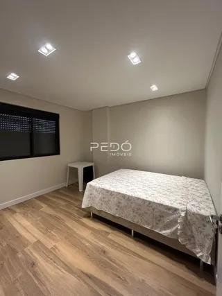 Quarto com cama e piso de madeira clara.