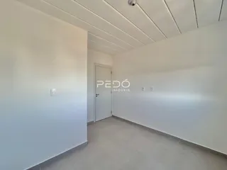 Interior de um corredor com paredes brancas e teto de painéis.