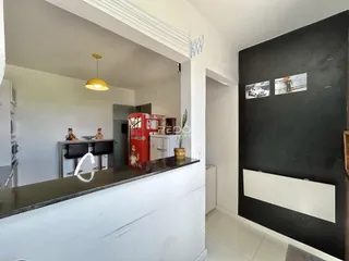 Vista de uma cozinha moderna com bancada escura e paredes brancas.