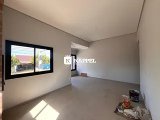Sala ampla e vazia com paredes brancas e piso claro.