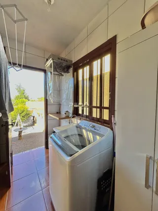 Foto de um interior mostrando uma máquina de lavar e uma porta de madeira.