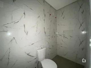 Foto do interior de um banheiro com revestimento de mármore nas paredes.