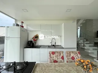 Cozinha moderna com armários brancos e bancada escura em apartamento no Brasil.