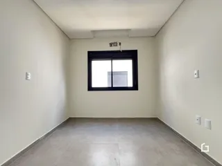 Foto de um ambiente interno vazio com paredes brancas e piso de concreto.