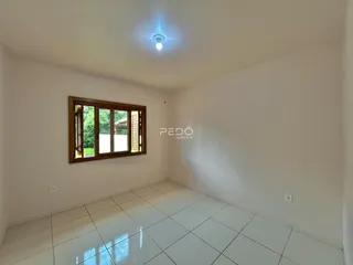 Ambiente interno de uma sala com piso de cerâmica branca e janela de madeira.