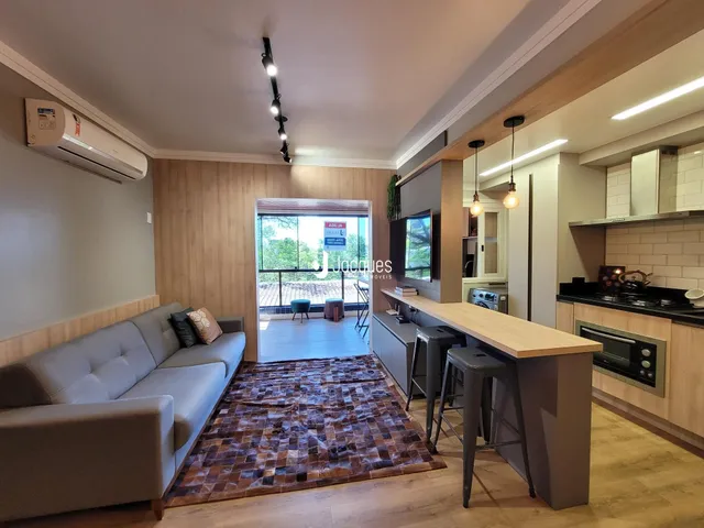 Sala de estar com sofá e piso de madeira, com vista para o exterior.