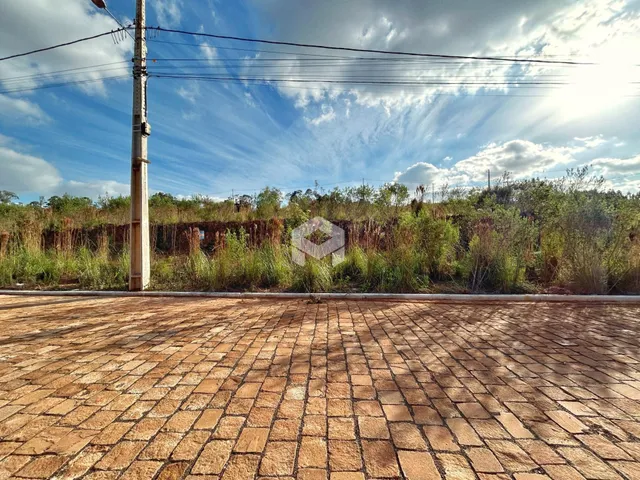 Vista externa de um pátio pavimentado com vegetação ao fundo.