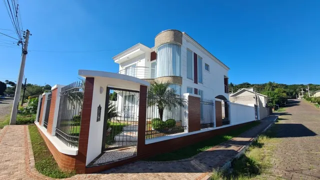 Fachada de uma casa branca com muro e portão em Lajeado, Brasil.