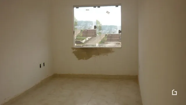 Ambiente interno de um cômodo vazio com paredes brancas e piso claro.