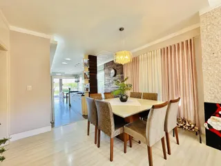 Sala de jantar com mesa de madeira e cadeiras em um ambiente claro.