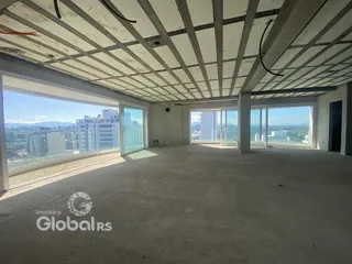 Vista interna de um espaço com estrutura de concreto e grandes janelas.