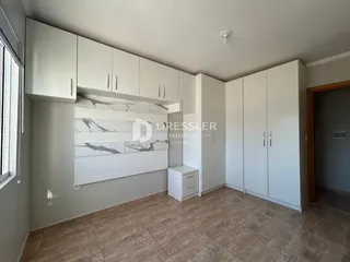 Interior de uma sala com armários brancos e parede de mármore na Lajeado.
