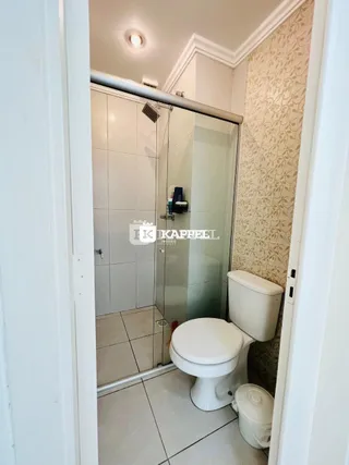 Foto de um banheiro com box de vidro e piso cerâmico.