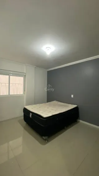 Quarto com cama grande e paredes brancas em um imóvel.