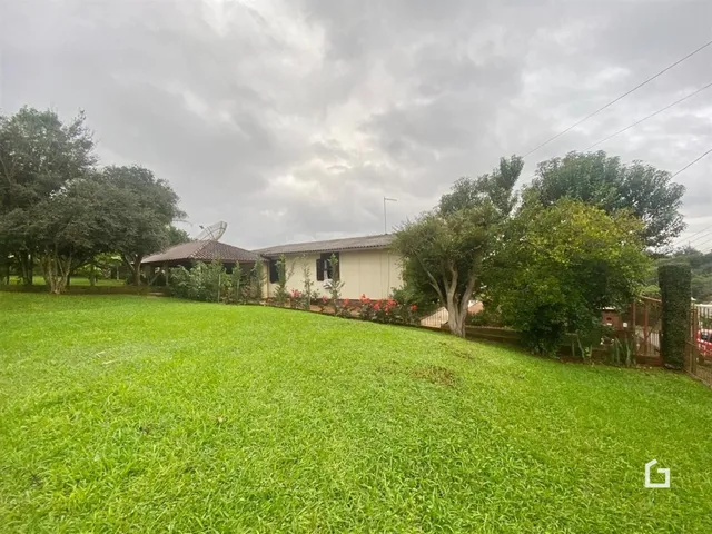 Vista externa de uma casa com gramado verde e vegetação ao redor.