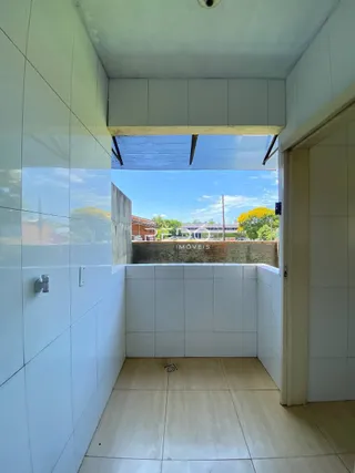 Parede interna com piso claro e abertura para o exterior de uma residência.