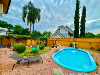 Vista externa de uma propriedade com piscina e jardim.