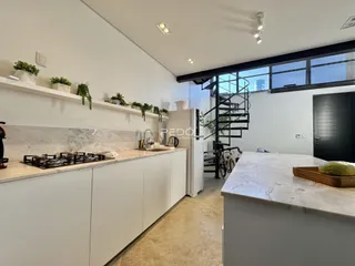 Cozinha moderna com armários brancos e bancadas claras.