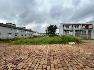 Vista externa de uma área pavimentada com tijolos em frente a edifícios residenciais.
