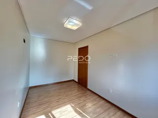 Vista interna de um corredor com piso de madeira e porta de madeira.