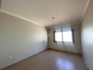 Ambiente interno de uma sala com piso de madeira clara e janela.