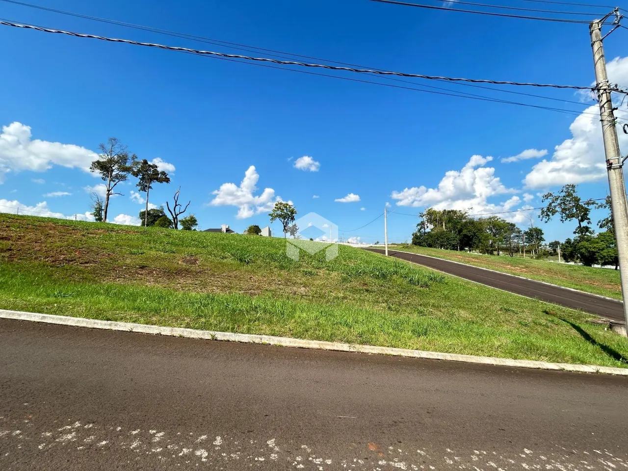 Vista de uma colina verde com uma estrada no primeiro plano.
