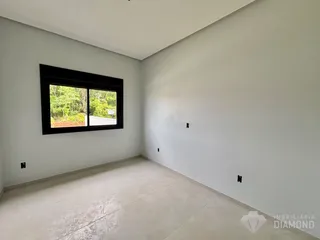 Vista interna de uma sala com parede branca e piso de cerâmica.