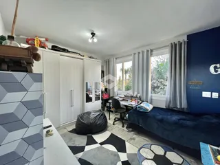 Ambiente interno de uma sala de estar com piso geométrico e armários brancos.