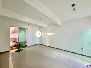 Esta é uma foto de uma sala ampla com piso de cerâmica clara e paredes brancas.