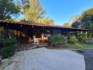 Vista da fachada de uma residência com área coberta e jardim.