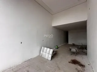 Interior de um espaço com paredes brancas e piso de concreto aparente.