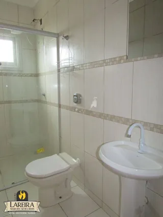 Foto de um banheiro com azulejos brancos e louças sanitárias.