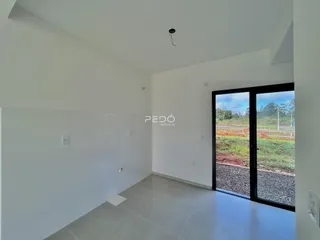 Interior de uma sala com piso de cerâmica e porta de vidro para o exterior.
