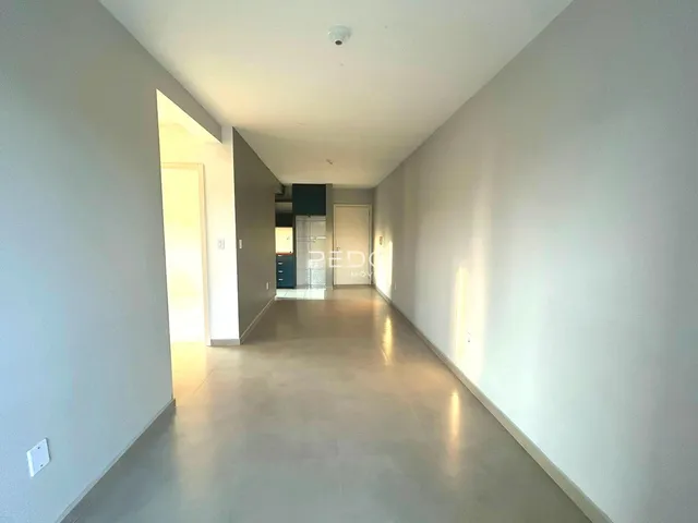 Corredor interno de uma residência com paredes brancas e piso claro.