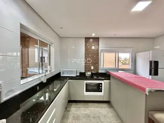Vista da cozinha com armários brancos e bancadas escuras.