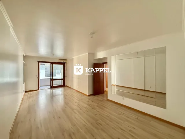 Uma sala de estar com piso de madeira e portas de vidro que dão acesso ao exterior.