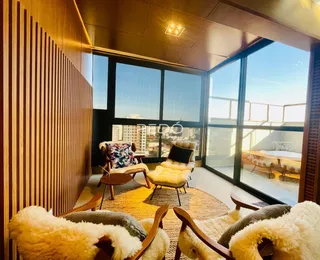Sala de estar com paredes de madeira e grandes janelas que dão vista para a paisagem.