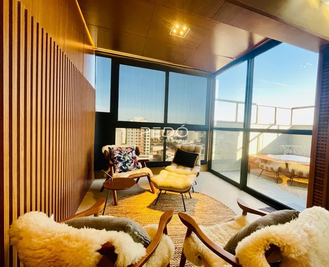 Sala de estar com paredes de madeira e grandes janelas que dão vista para a paisagem.
