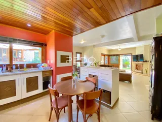 Sala de jantar com mesa de madeira e janelas em um imóvel no Brasil.