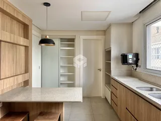 Interior de uma cozinha com armários de madeira e bancada clara.