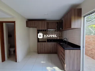 Cozinha com armários de madeira e bancada escura em um ambiente claro.